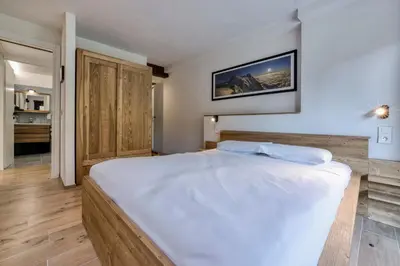 a bedroom with a large white bed and a bathroom at Nid du Pic - Cozy alpine retreat with private garden in Chamonix in Chamonix-Mont-Blanc