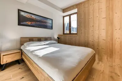 a bed in a room with a wooden wall at Nid du Pic - Cozy alpine retreat with private garden in Chamonix in Chamonix-Mont-Blanc