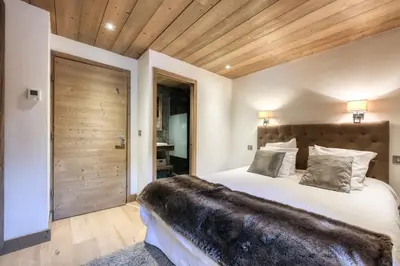 a bedroom with a large bed and a wooden ceiling at Le Cédron, demi-chalet centre pièton Megève in Megève