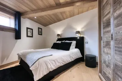 a bedroom with a large bed and a wooden wall at Le Cédron, demi-chalet centre pièton Megève in Megève