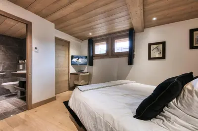 a bedroom with a large bed and a television at Le Cédron, demi-chalet centre pièton Megève in Megève