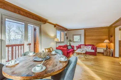 a living room with a wooden table and chairs at Appartement Mercier - Welkeys in Megève