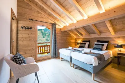 two beds in a wooden room with a balcony at L'Eterle - Grand chalet avec terrasse et jardin in Les Contamines-Montjoie