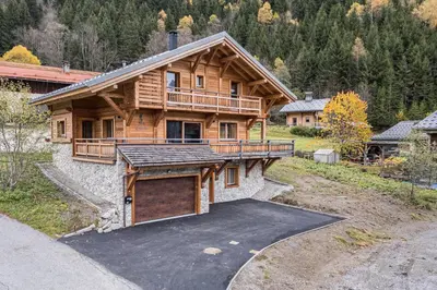 a large wooden house with a driveway in front of it at L'Eterle - Grand chalet avec terrasse et jardin in Les Contamines-Montjoie