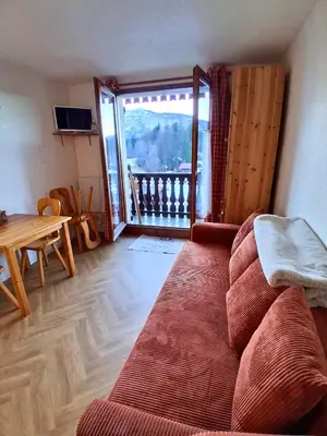 a living room with a couch and a table and a balcony at Studio SnowCarroz with a view for 4 people in Arâches-la-Frasse
