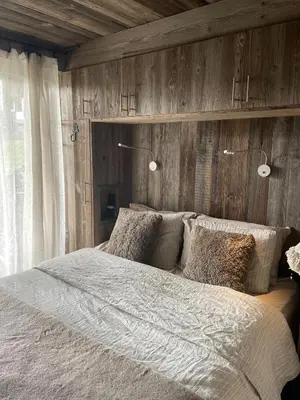 a bedroom with a large bed with wooden walls at Cimes Lodge - Wood & Mountain in Demi-Quartier