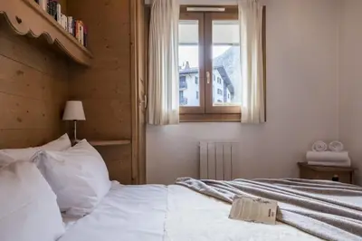 a bedroom with a white bed with a window at Capucins in Chamonix-Mont-Blanc