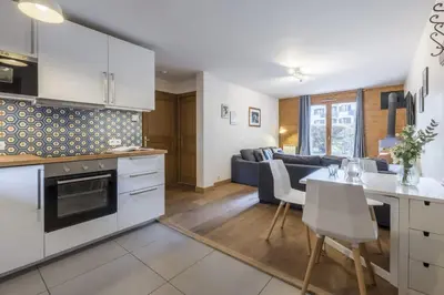 a kitchen and living room with white cabinets and a table at Capucins in Chamonix-Mont-Blanc