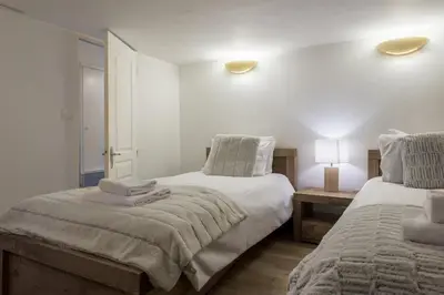 a bedroom with two beds and a table with a lamp at Chalet Cusco in Servoz
