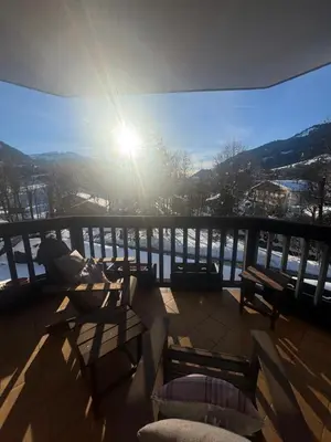 a balcony with chairs and the sun in the sky at LiHam Alpine Suite in Megève