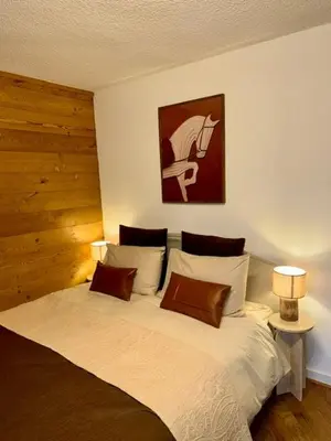 a bedroom with a bed with two lamps and a painting at LiHam Alpine Suite in Megève