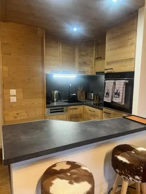 a kitchen with a counter and two stools in it at LiHam Alpine Suite in Megève