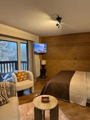 a bedroom with a bed and a couch and a tv at LiHam Alpine Suite in Megève