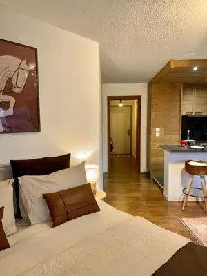 a bedroom with a white bed and a kitchen at LiHam Alpine Suite in Megève