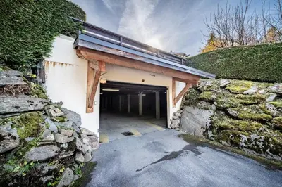 a garage with a stone wall next to a building at Apartment Snowdust Megève - by EMERALD STAY in Megève