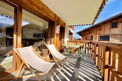 a deck with chairs and a table on a house at Bright apartment with balcony and stunning views in Megève