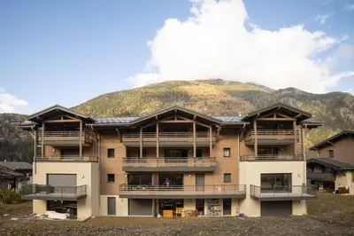 a large apartment building with a mountain in the background at Cosmiques A203 - New & Mont Blanc view in Les Houches