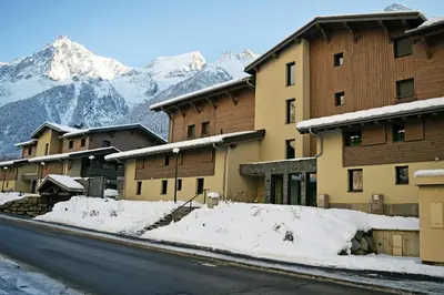 a snowy street with buildings and mountains in the background at Cosmiques A203 - New & Mont Blanc view in Les Houches