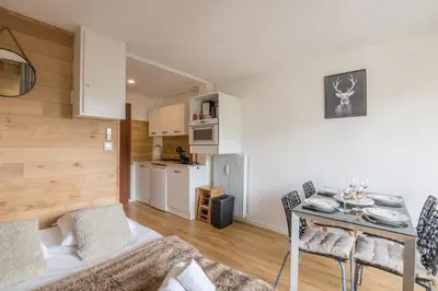 a living room with a table and a kitchen at Studio Espérance - Welkeys in Megève