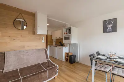 a living room with a table and a kitchen at Studio Espérance - Welkeys in Megève