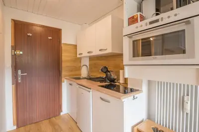 a kitchen with white cabinets and a sink at Studio Espérance - Welkeys in Megève