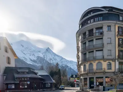 a building with a snow covered mountain in the background at Diamond - Hyper Central 2 Bedrooms - Magnificent Views - By Cozee Rentals in Chamonix-Mont-Blanc