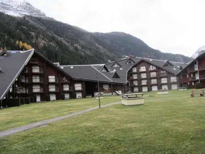 a large building with a grass field in front of a mountain at Résidence L'enclave - Enclave I599 MAE-9743 in Les Contamines-Montjoie