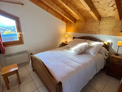 a bedroom with a large bed with a wooden ceiling at Confortable T3 au cœur de Samoëns avec WIFI et parking - FR-1-629-152 in Samoëns