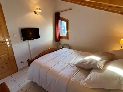 a bedroom with a bed and a tv on the wall at Confortable T3 au cœur de Samoëns avec WIFI et parking - FR-1-629-152 in Samoëns