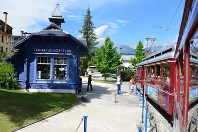 a red train parked in front of a blue building at Refuge des Cols Verts Parking Cozy Relaxing in Saint-Gervais-les-Bains
