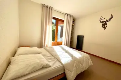 a bedroom with a bed with a deer head on the wall at Bright apartment in Combloux near ski in Combloux