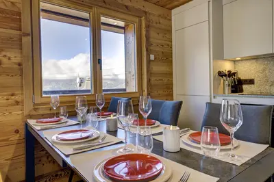 a kitchen with a counter and a table with chairs at Arbois Elégance - Ski aux pieds in Megève