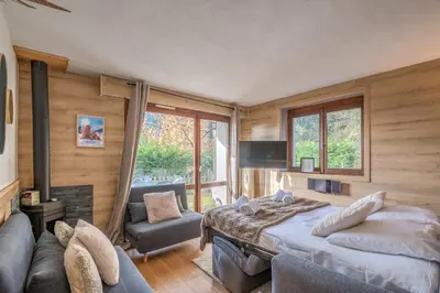 a bedroom with a bed and a couch and a tv at Appartement Perret - Welkeys in Megève