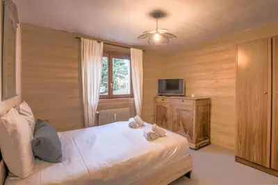 a bedroom with a large bed and a television at Appartement Perret - Welkeys in Megève
