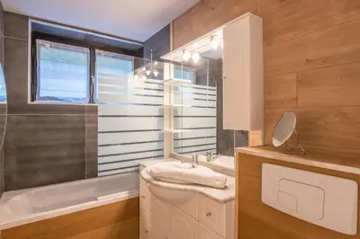 a bathroom with a sink and a toilet and a mirror at Appartement Perret - Welkeys in Megève