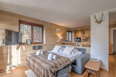 a bedroom with a large bed and a kitchen at Appartement Perret - Welkeys in Megève