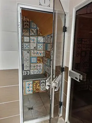a shower in a bathroom with a tile wall at Au cœur de Chamonix – La Ginabelle, Calme avec Piscine, Sauna & Garage in Chamonix-Mont-Blanc