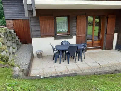 a patio with a table and chairs in front of a house at Studio cosy avec terrasse, 4 pers, parking privatif - FR-1-836-35 in Arâches-la-Frasse