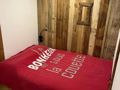 a red blanket on a bed with a wooden wall at Appartement moderne en centre-ville avec parking et animaux admis - 6 pers. - FR-1-836-49 in Arâches-la-Frasse