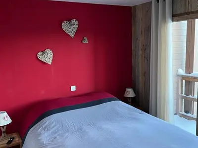a bedroom with a red wall with hearts on it at Appartement moderne en centre-ville avec parking et animaux admis - 6 pers. - FR-1-836-49 in Arâches-la-Frasse