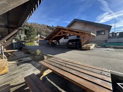 a wooden bench sitting in front of a building at Appartement de charme dans chalet rénové - Animaux et parking - FR-1-836-54 in Arâches-la-Frasse