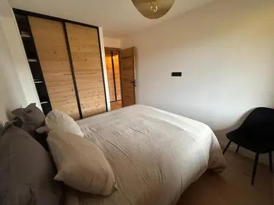 a bedroom with a white bed and a chair at Nouveau ! Appartement de standing 3 chambres avec balcon et parking couvert - FR-1-836-42 in Arâches-la-Frasse
