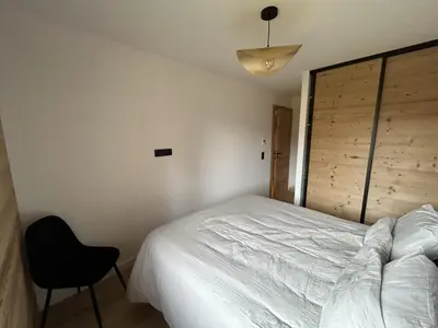 a bedroom with a white bed and a chair at Nouveau ! Appartement de standing 3 chambres avec balcon et parking couvert - FR-1-836-42 in Arâches-la-Frasse