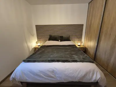 a bedroom with a large bed with two lamps on tables at Appartement neuf 2 chambres avec parking, rez-de-jardin - FR-1-836-52 in Arâches-la-Frasse