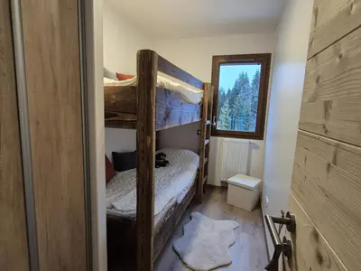 a bedroom with two bunk beds and a window at Appartement neuf 2 chambres avec parking, rez-de-jardin - FR-1-836-52 in Arâches-la-Frasse