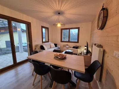 a dining room and living room with a table and chairs at Appartement neuf 2 chambres avec parking, rez-de-jardin - FR-1-836-52 in Arâches-la-Frasse