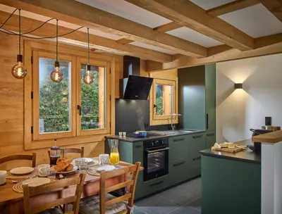 a kitchen with green cabinets and a table with chairs at Chalet Juno - Chamonix All Year in Chamonix-Mont-Blanc