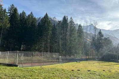 a tennis court in a field with trees and mountains at Bright apartment for 6 people in Chamonix in Chamonix-Mont-Blanc