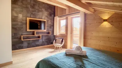 a bedroom with a bed and a tv on a wall at Chalet des Pres- 3 chambres - JAILLET - in Demi-Quartier