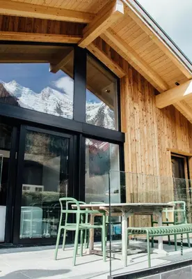 a glass table and chairs on a patio with mountains at New Chalet Facing The Aiguilles De Chamonix in Les Houches
